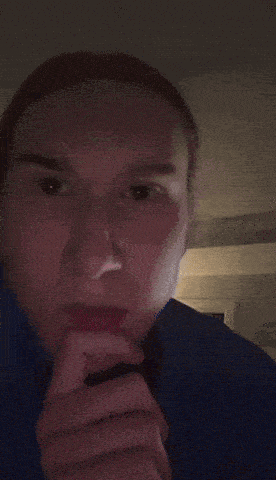 a man in a blue shirt is making a funny face with his fingers