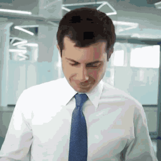 a man in a white shirt and blue tie looks down at something