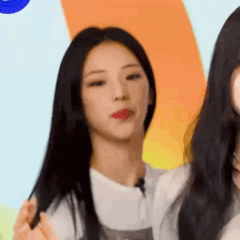 a woman with long black hair is standing next to another woman and making a funny face .