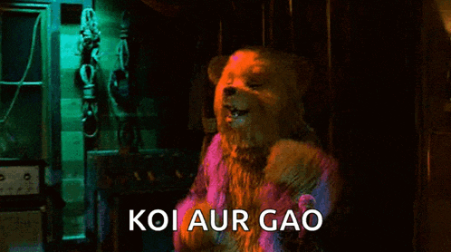 a teddy bear is dancing in a dark room with the words koi aur gao written below it .