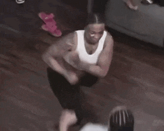 a couple of men are fighting on a wooden floor .