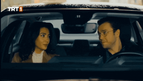 a man and a woman are sitting in a car with trt1 written on the bottom