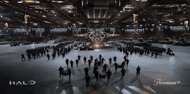 a large group of people are running in a hallway with the halo logo