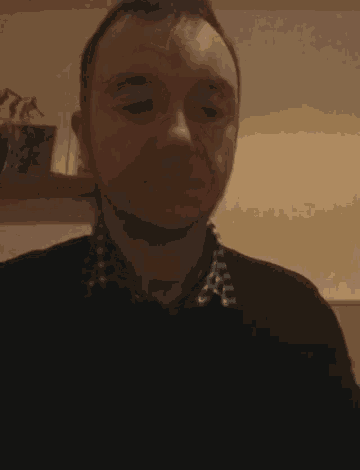 a man wearing a plaid shirt and a black sweater