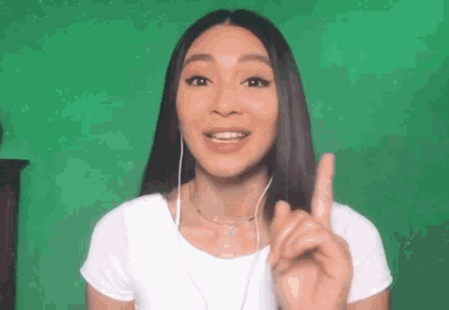 a woman wearing headphones and a white shirt is pointing her finger up .