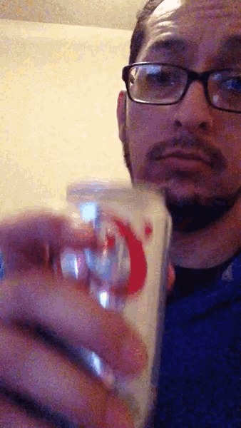 a man wearing glasses is holding a glass with a red crescent moon on it