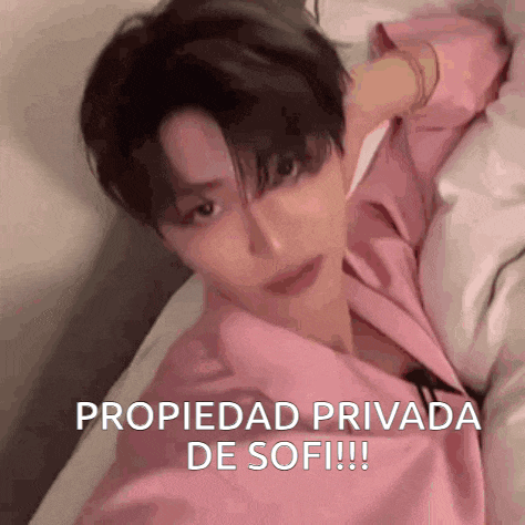 a man in a pink shirt is laying on a bed with the words propiedad privada de sofi written on the bottom .