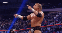 a wrestler in a wrestling ring pointing at the crowd