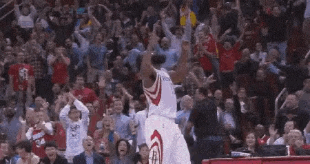 a basketball player is jumping in the air in front of a crowd of fans .