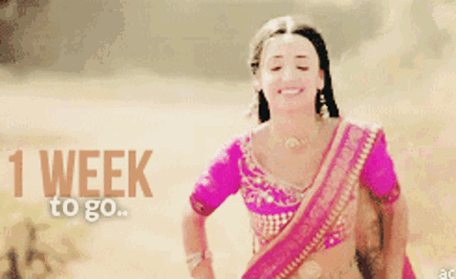 a woman in a pink top is smiling with the words 1 week to go behind her