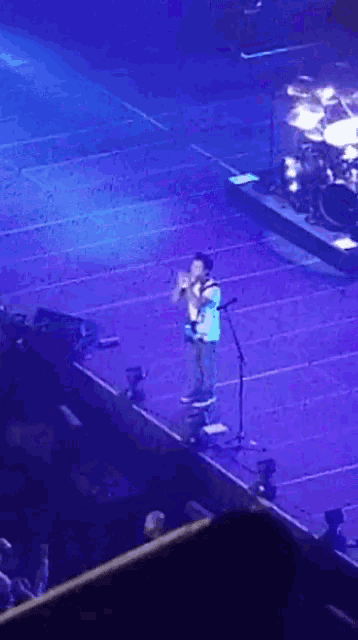 a man singing into a microphone on a stage in front of a crowd