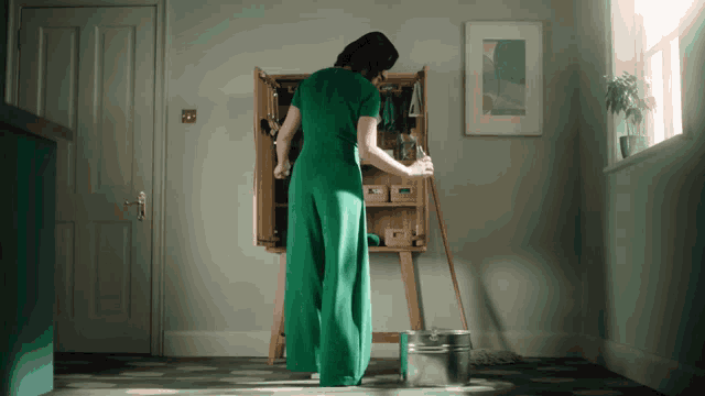 a woman in a green dress mopping the floor