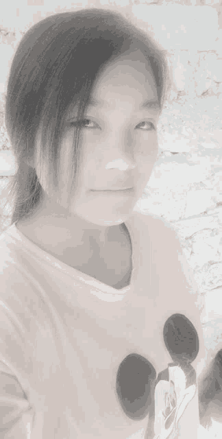 a black and white photo of a girl wearing a mickey mouse shirt .