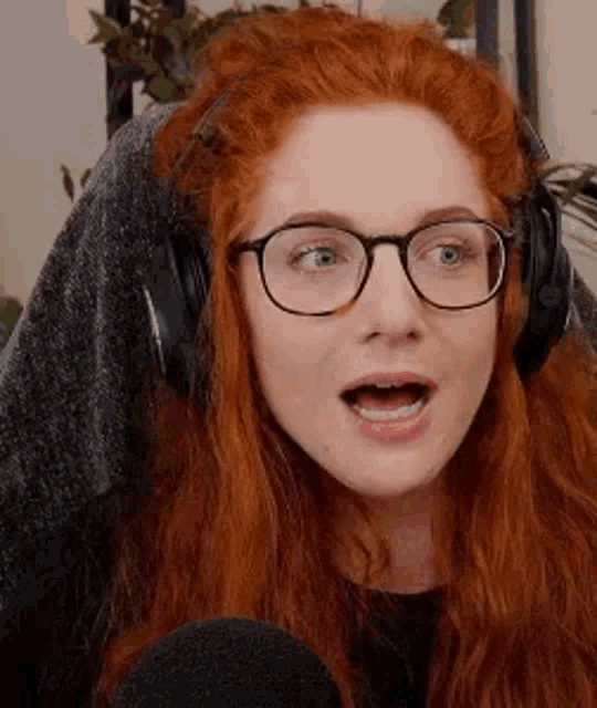 a woman with red hair is wearing glasses and headphones .