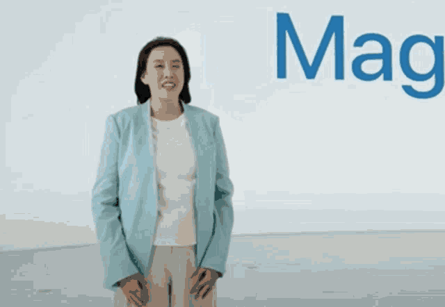 a woman in a blue jacket and white shirt is standing in front of a white wall with the word mars on it .