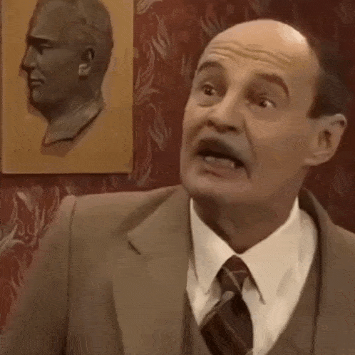 a man in a suit and tie with the words " e bas bi to volo vidi it " below him