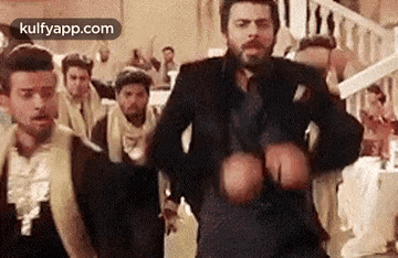 a man with a beard is dancing in front of a crowd of people .