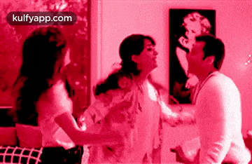 a man and two women are dancing in a room with a picture of marilyn monroe on the wall .
