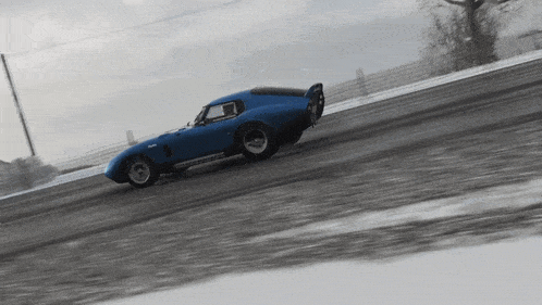 a blue car is driving down a snowy road