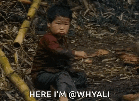 a young boy is sitting on the ground in a pile of bamboo sticks .