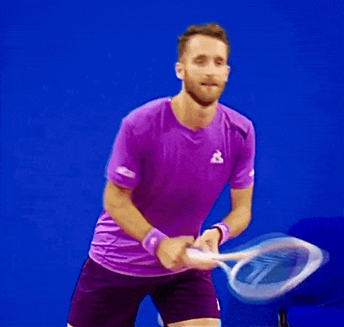 a blurry image of a man in a purple shirt holding a tennis racket