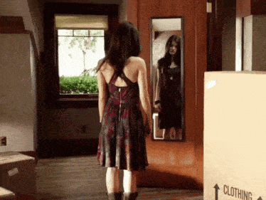 a woman is standing in front of a mirror next to a clothing box