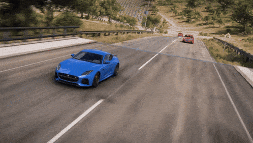 a blue car is driving down a road with a red car behind it
