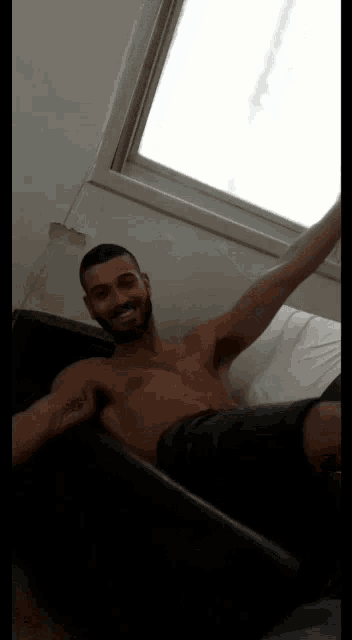 a shirtless man is laying on a bed with his arm outstretched