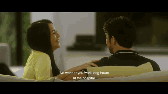 a man and a woman are sitting on a couch with the words no wonder you work long hours at the hospital