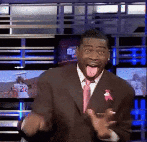 a man in a suit and tie is sticking his tongue out in front of a television screen .
