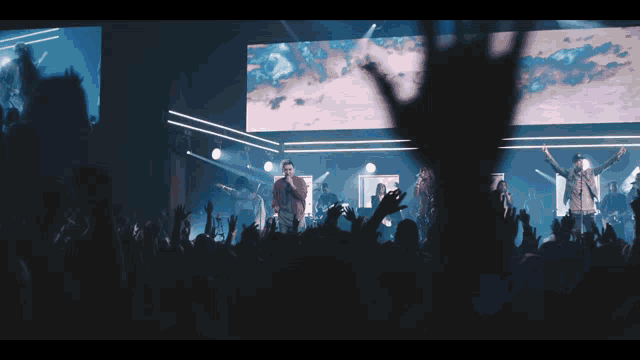 a man singing into a microphone in front of a crowd of people