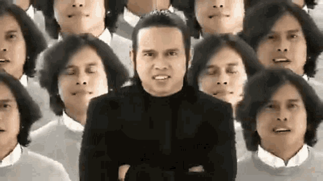 a man in a black suit is standing in front of a crowd of people with their heads visible .