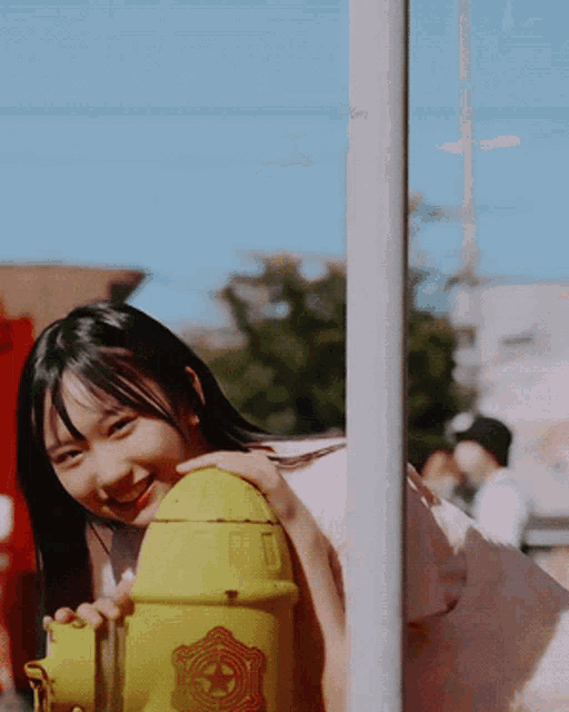 a woman is holding a yellow fire hydrant with a star on it