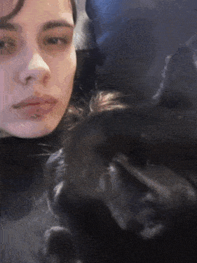 a close up of a woman 's face with a black dog behind her