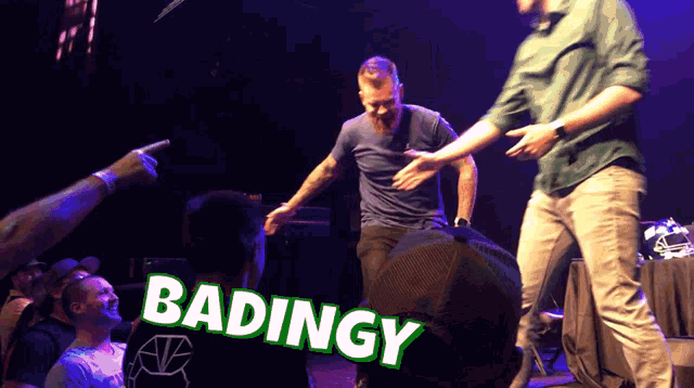 a group of men are dancing on a stage and the word badingy is on the back of a shirt