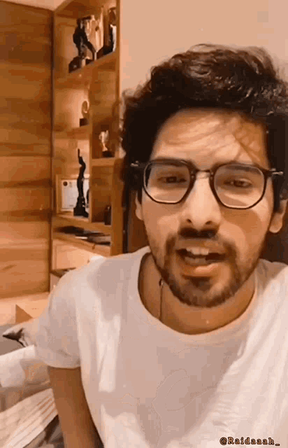 a man with glasses and a beard is wearing a white t-shirt