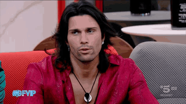 a man with long hair is sitting on a couch with #gfvip written on the bottom right