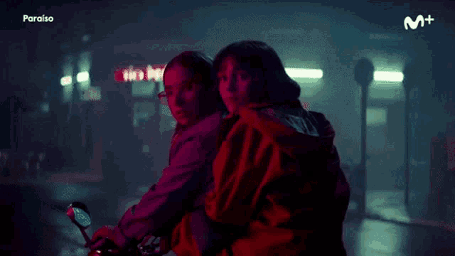 two girls are riding a motorcycle with the word paraiso on the bottom right corner