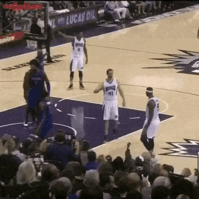 a basketball game is being played in front of a crowd with a lucas oil ad in the background .