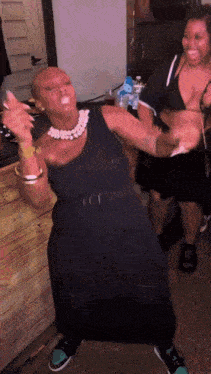 a woman in a black dress is dancing with another woman