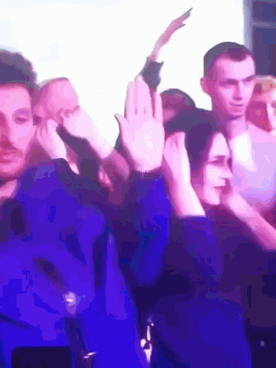 a group of people dancing in a dark room with purple lights