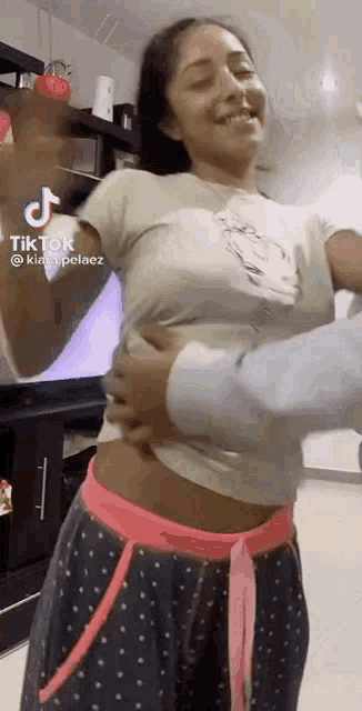 a woman in a white shirt and pink polka dot pants is being held by a man .
