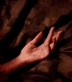 a close up of a person 's hand reaching out towards something .