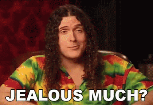 a man with long curly hair is wearing a tie dye shirt and saying jealous much