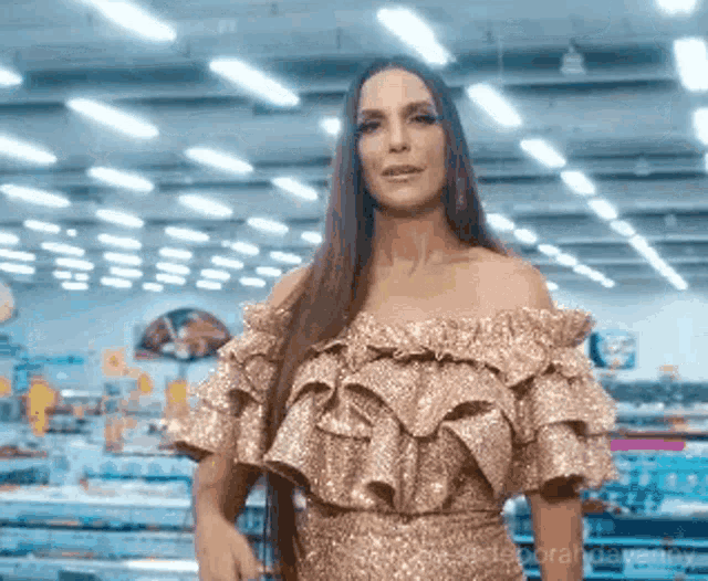 a woman in a gold off the shoulder dress is standing in a store .