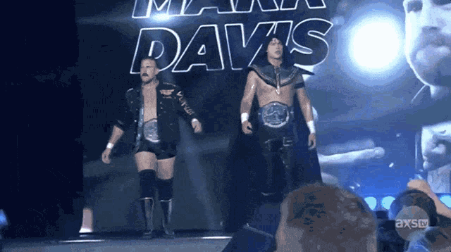 two wrestlers are walking in front of a banner that says max davis