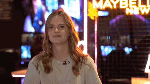 a woman is standing in front of a maybelline sign