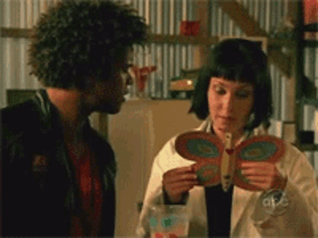 a man and a woman are looking at a butterfly in a book
