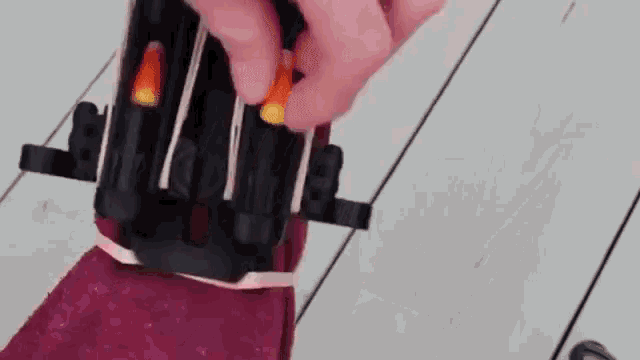 a person is holding a bottle of lipstick on a wooden surface .