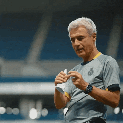 a man wearing a gray and yellow shirt with a watch on his wrist looks down